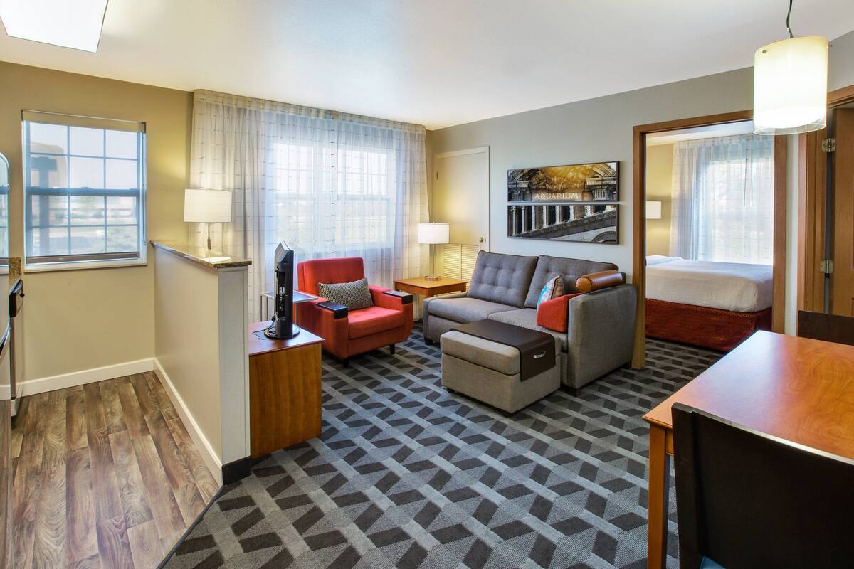 A hotel room with a sofa, armchair, ottoman, and a bed.