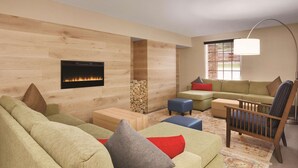 A modern living room with a fireplace, green and beige sofas, a wooden coffee table, and a floor lamp. - Country Inn & Suites by Radisson, Pigeon Forge South, TN (Pigeon Forge)