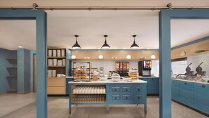A modern kitchen with blue cabinets, a central island with various appliances, and overhead lighting. - Country Inn & Suites by Radisson, Pigeon Forge South, TN (Pigeon Forge)