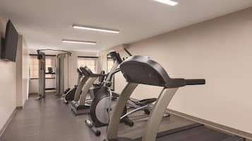 A gym with treadmills, a weight machine, and a TV mounted on the wall.