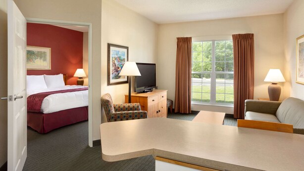 A hotel room with a bed, a desk, a television, and two chairs.