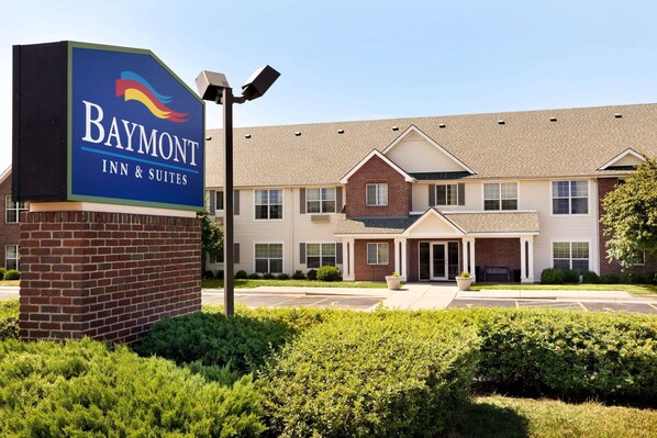 Stylish Baymont Inn & Suites features a brick facade, central entrance, and well-manicured grounds.