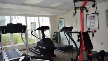 Un gimnasio con cintas de correr, elípticas y una estación Bowflex roja.