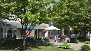 A residential house with a front porch, outdoor seating, and a barbecue grill. - Cresthill Suites Syracuse (East Syracuse)
