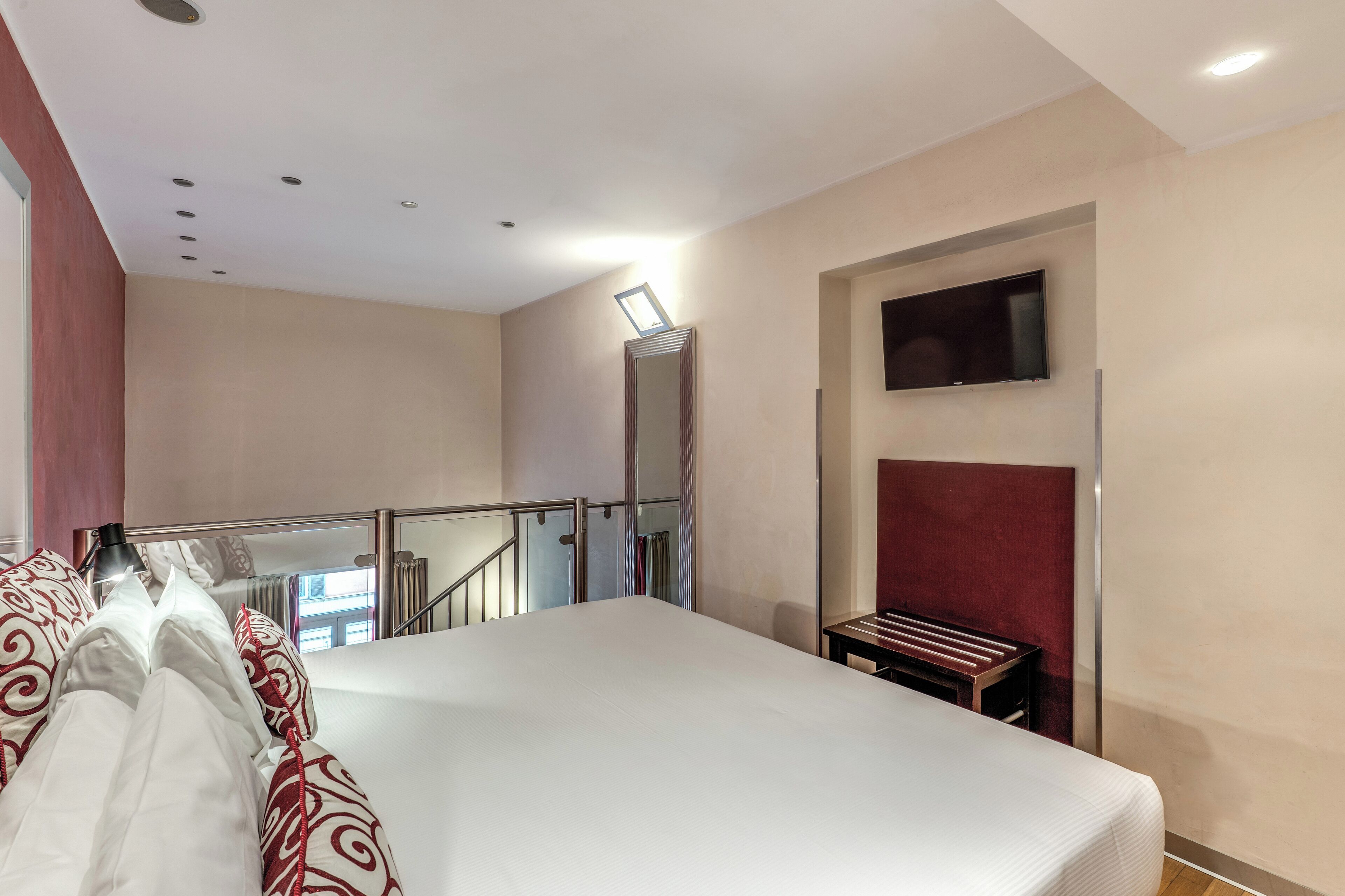 A hotel room with a large bed, a TV mounted on the wall, and a small table.