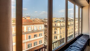 A room with large windows overlooking a cityscape with historic buildings. - La Griffe Hotel (Rome)