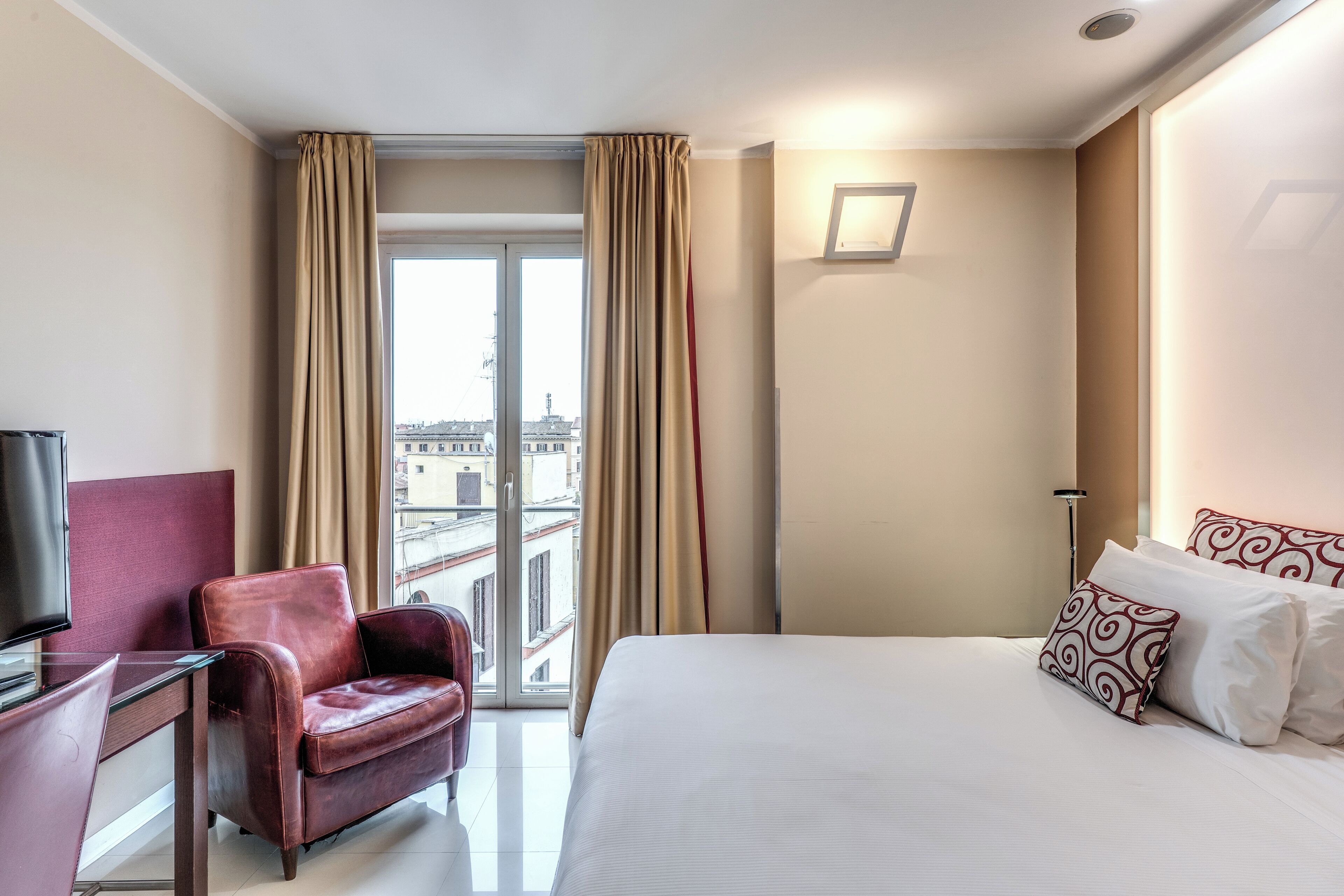 A hotel room with a bed, a desk, a chair, and a TV.