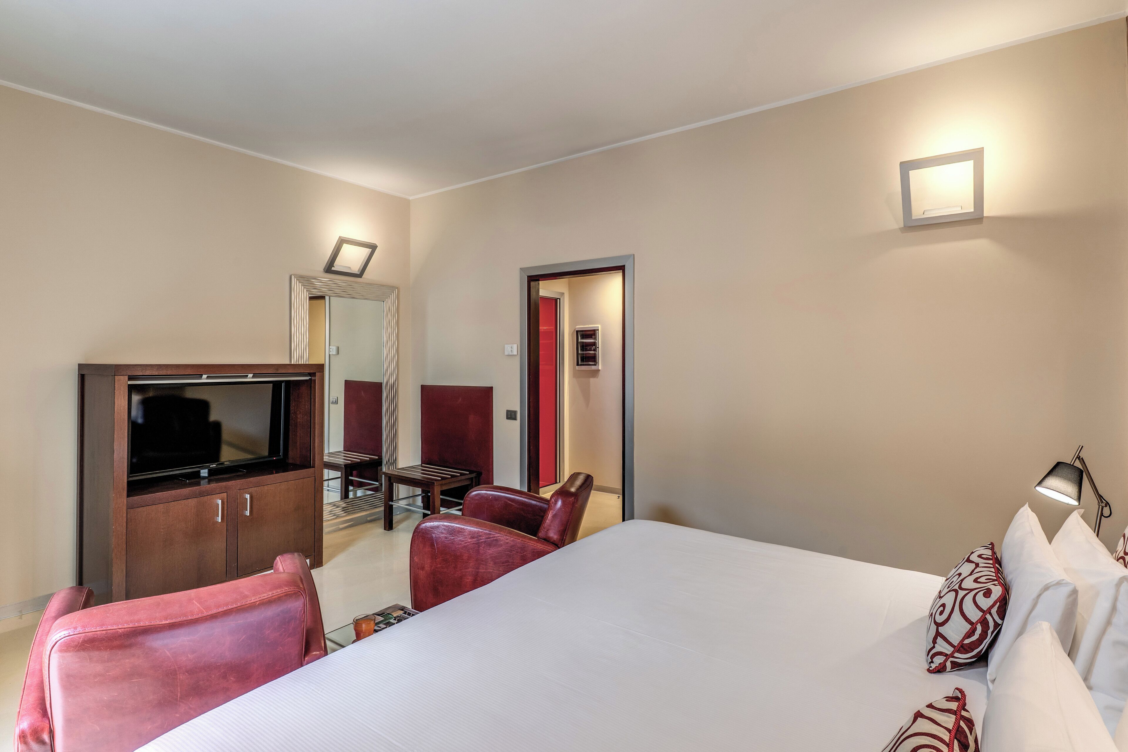Una camera d'albergo con un letto grande, una TV, una scrivania e una sedia.