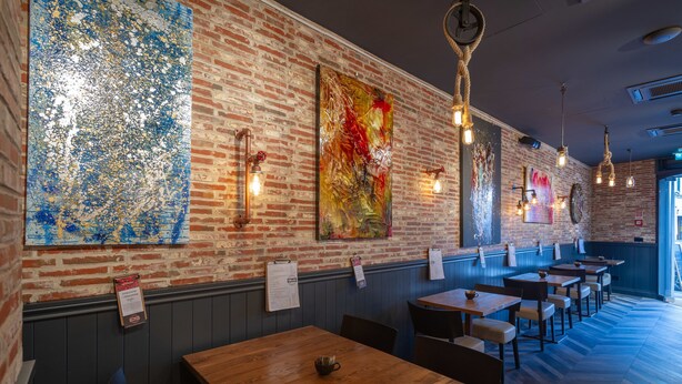 A restaurant interior with brick walls, wooden tables, and hanging light fixtures. - Hotel Boccaccio (Florence)