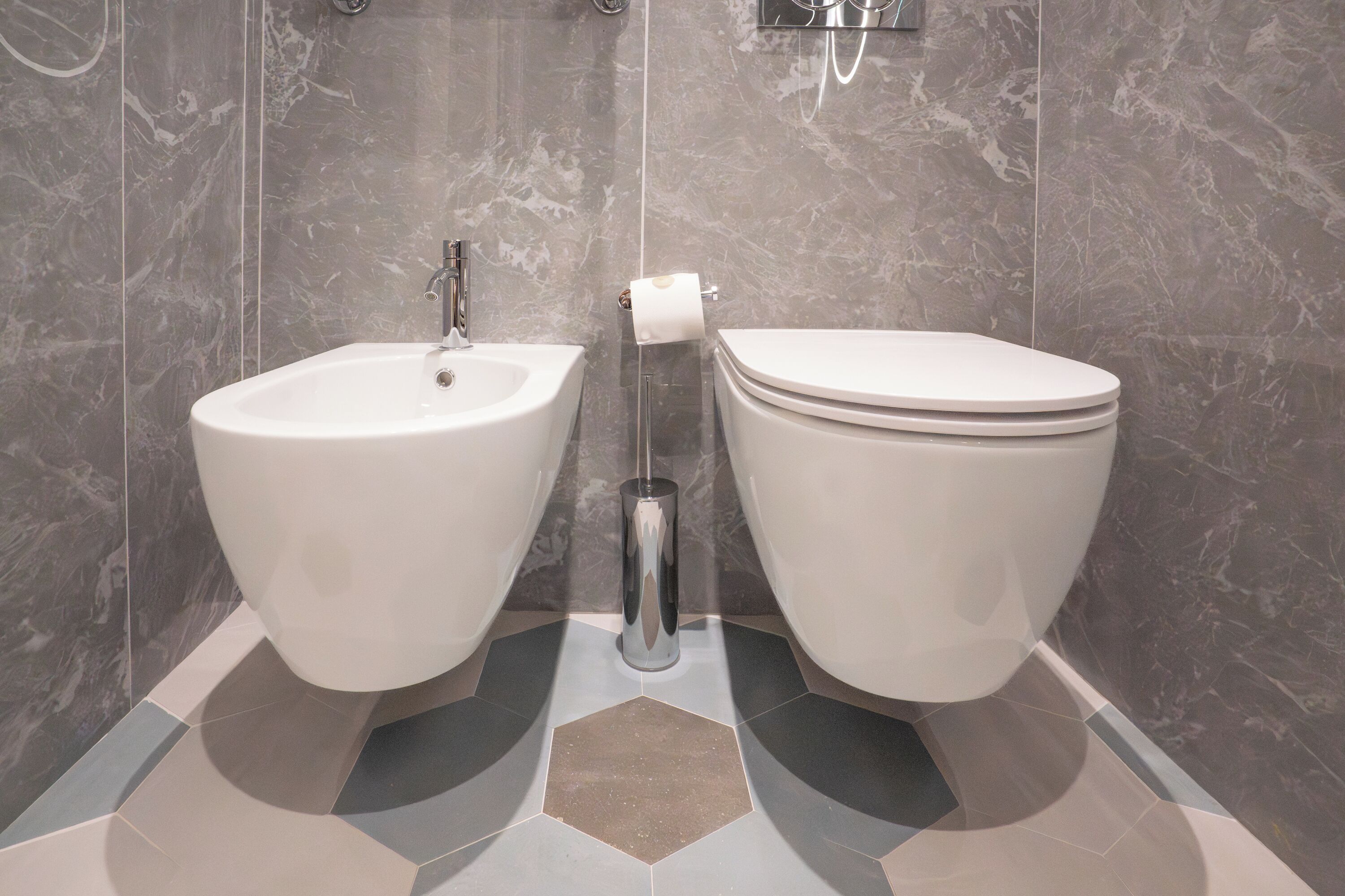 Ein Badezimmer mit integriertem Bidet, Toilette und Handtuchhalter.