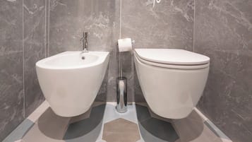 A bathroom with a bidet, toilet, and a towel rack.
