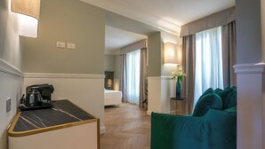 A hotel room with a green sofa, a small table with a kettle, a bed, and a lamp. - Il Malaspina (Florence)