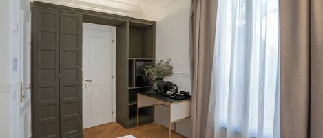 A hotel room with a bed, a desk with a coffee maker, a TV, and a door leading to a closet.