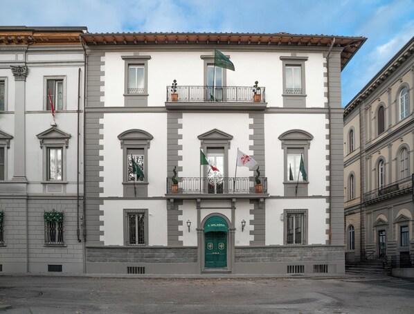 Un edificio con puerta verde, múltiples ventanas y balcones adornados con banderas.