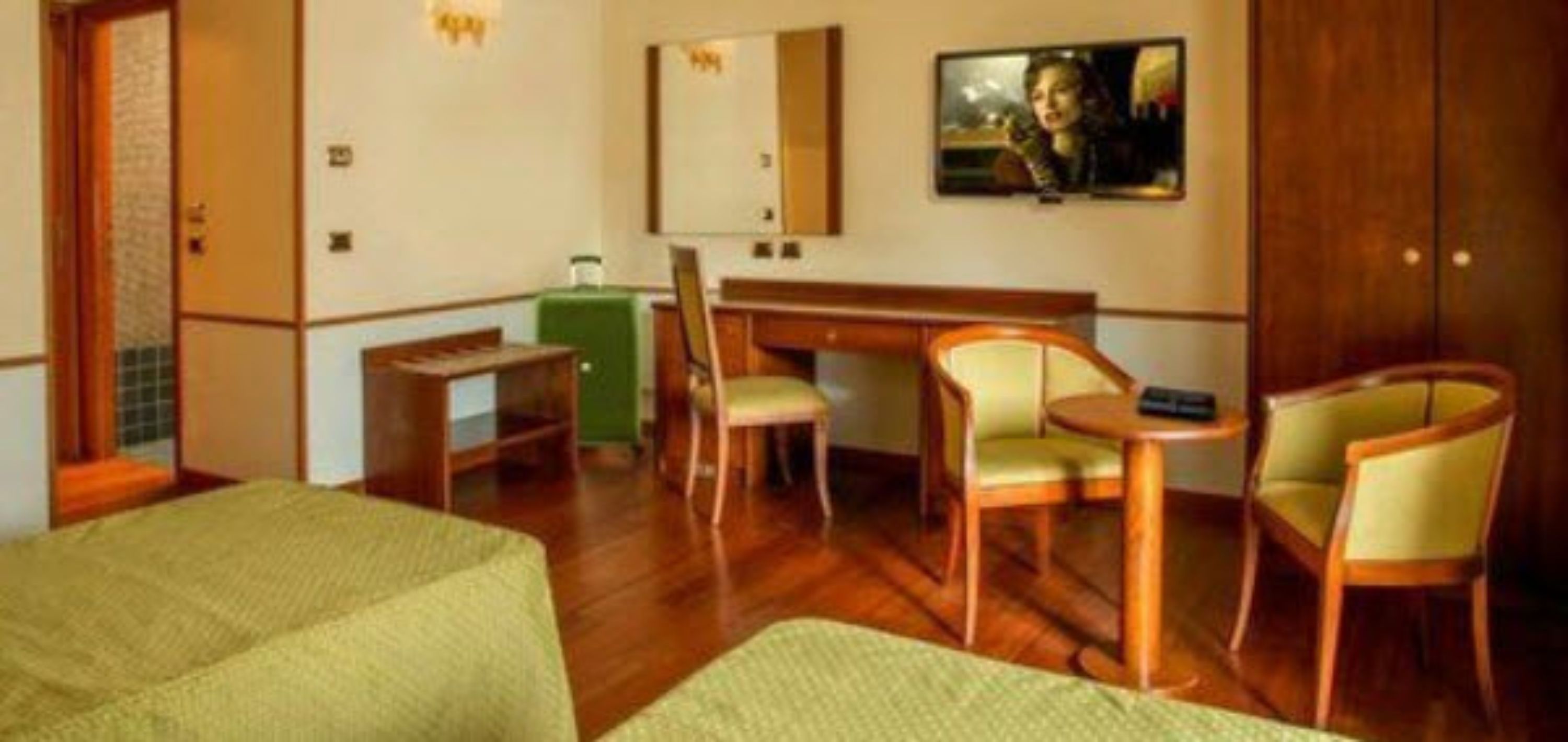 Ein Hotelzimmer mit einem Bett, einem Schreibtisch, zwei Stühlen, einem Spiegel und einem Fernseher.