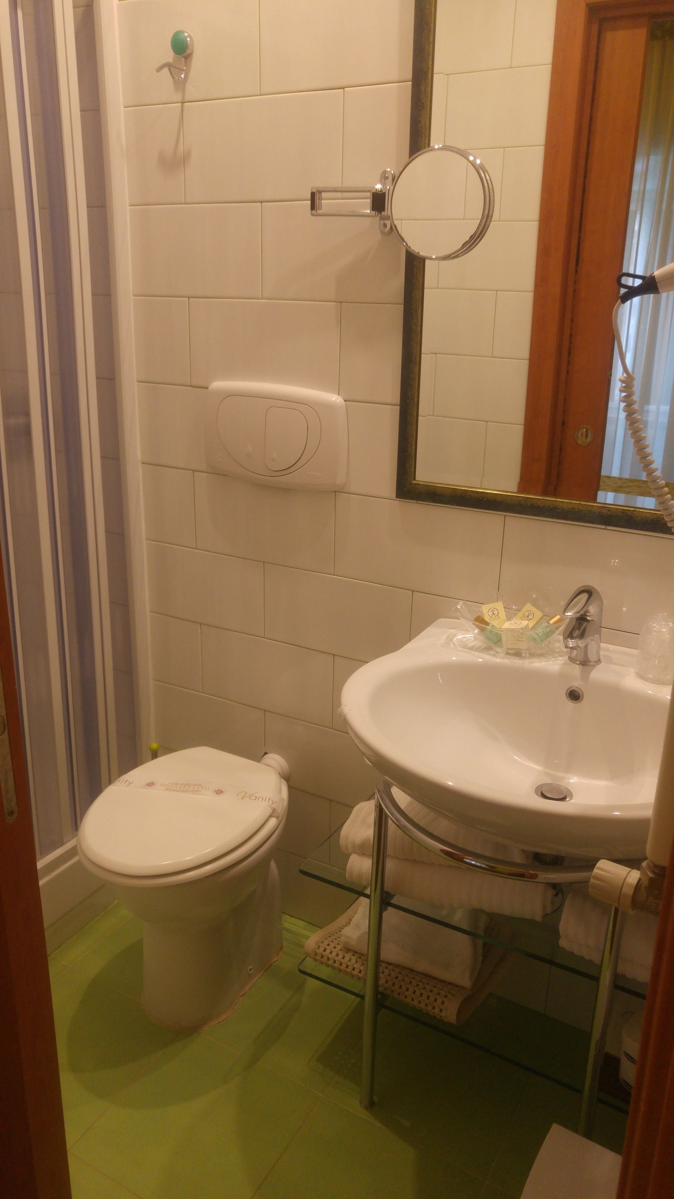 A bathroom with a toilet, sink, and a mirror.