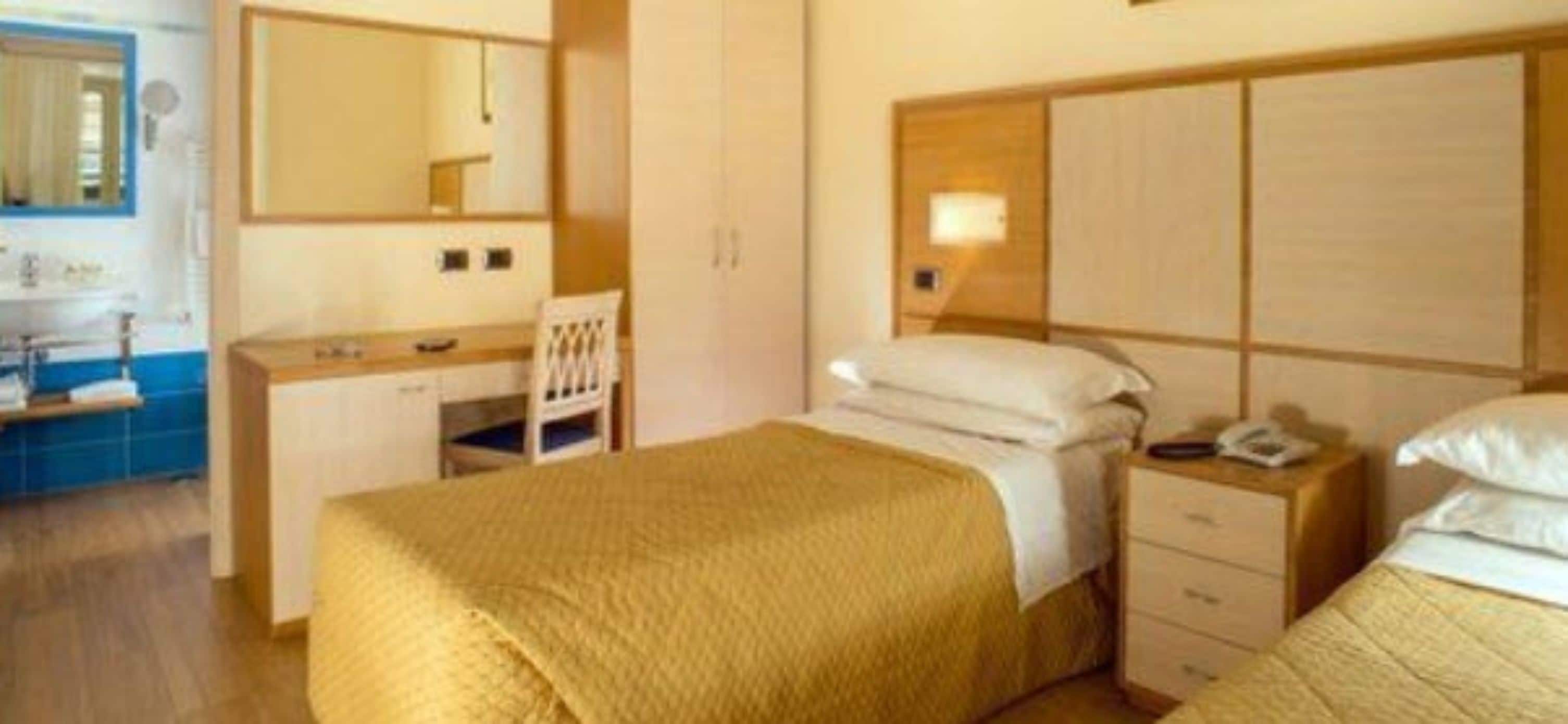 Una camera d'albergo con un letto, un comodino e uno specchio.