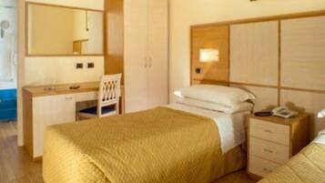 Una camera d'albergo con un letto, un comodino e uno specchio.