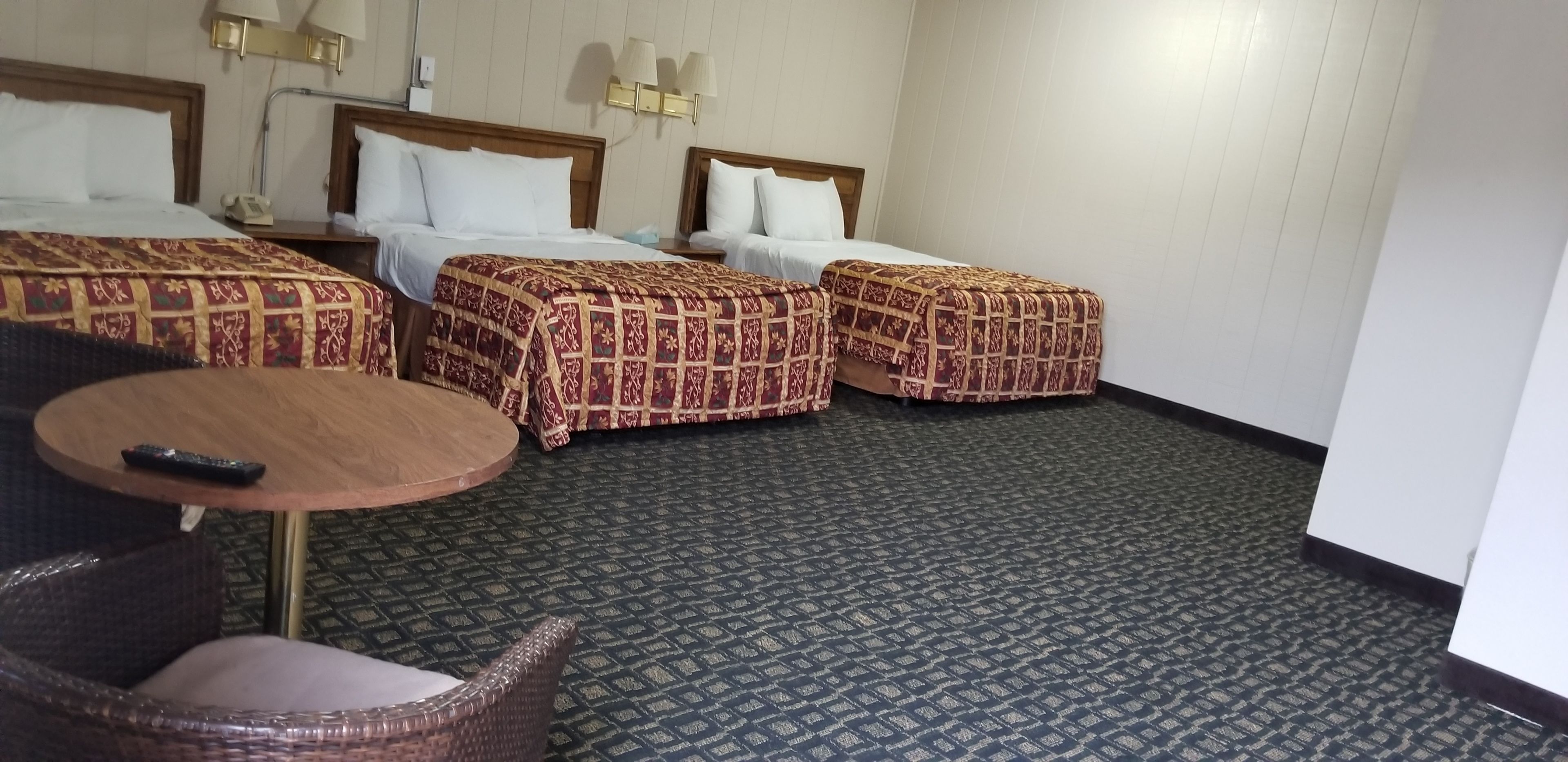 A hotel room with three beds, a round table, and a chair.