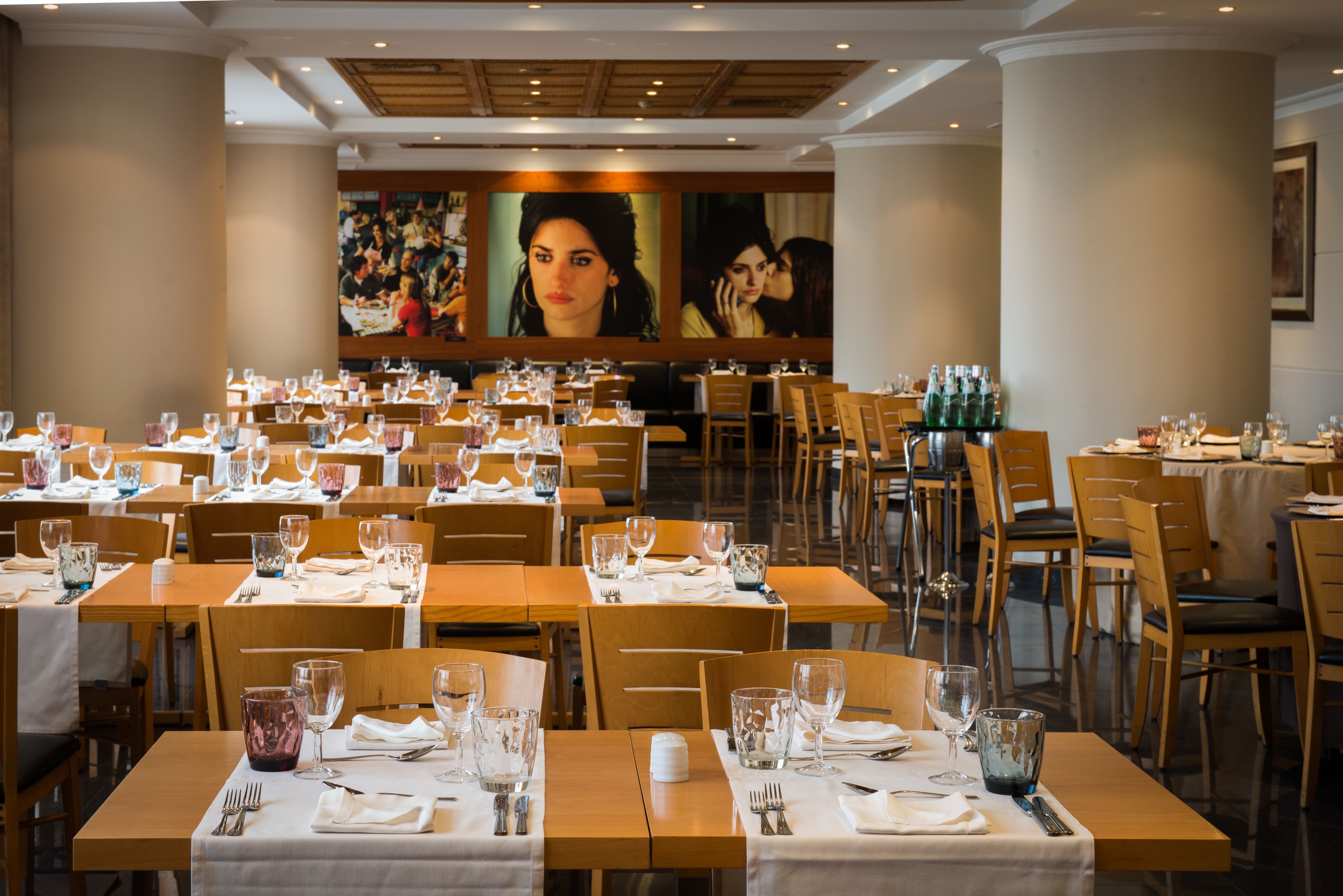 A restaurant with multiple tables set for dining, featuring a large mural on the back wall.