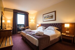 A hotel room with a large bed, a desk, a chair, a bedside table, and a window with curtains. -  Vila Gale Porto Centro Hotel (Porto)