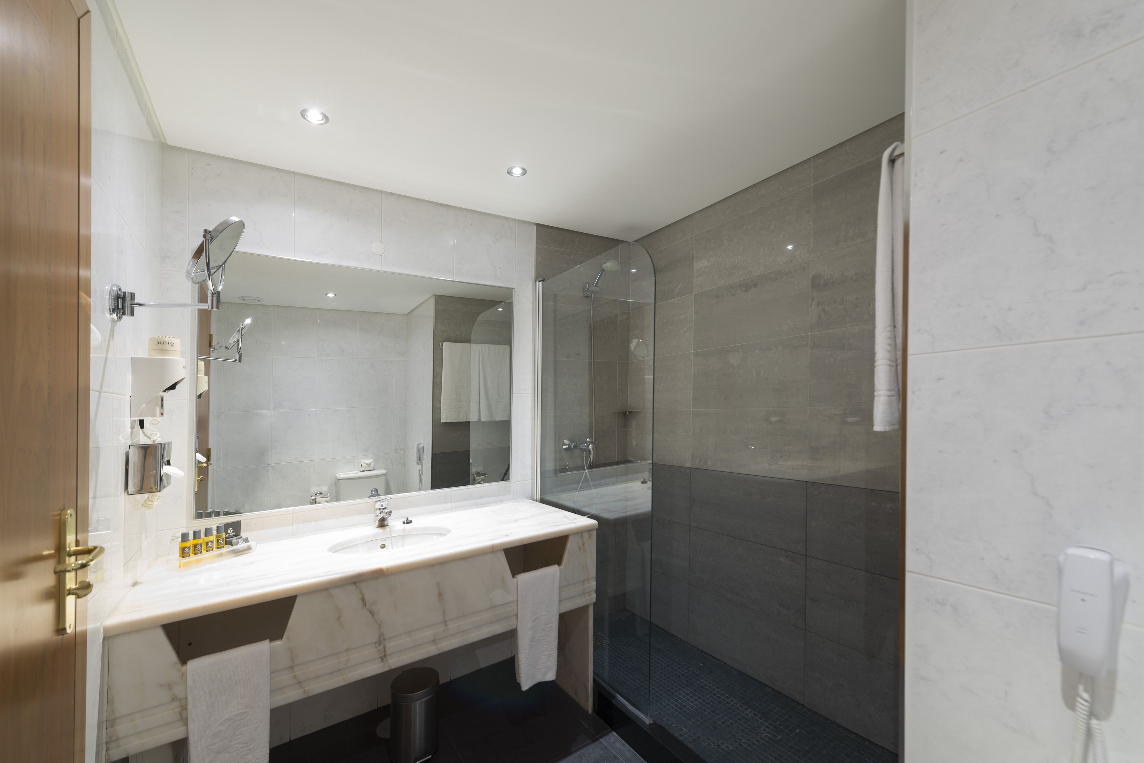 A modern bathroom with a large mirror, a sink, and a glass-enclosed shower.