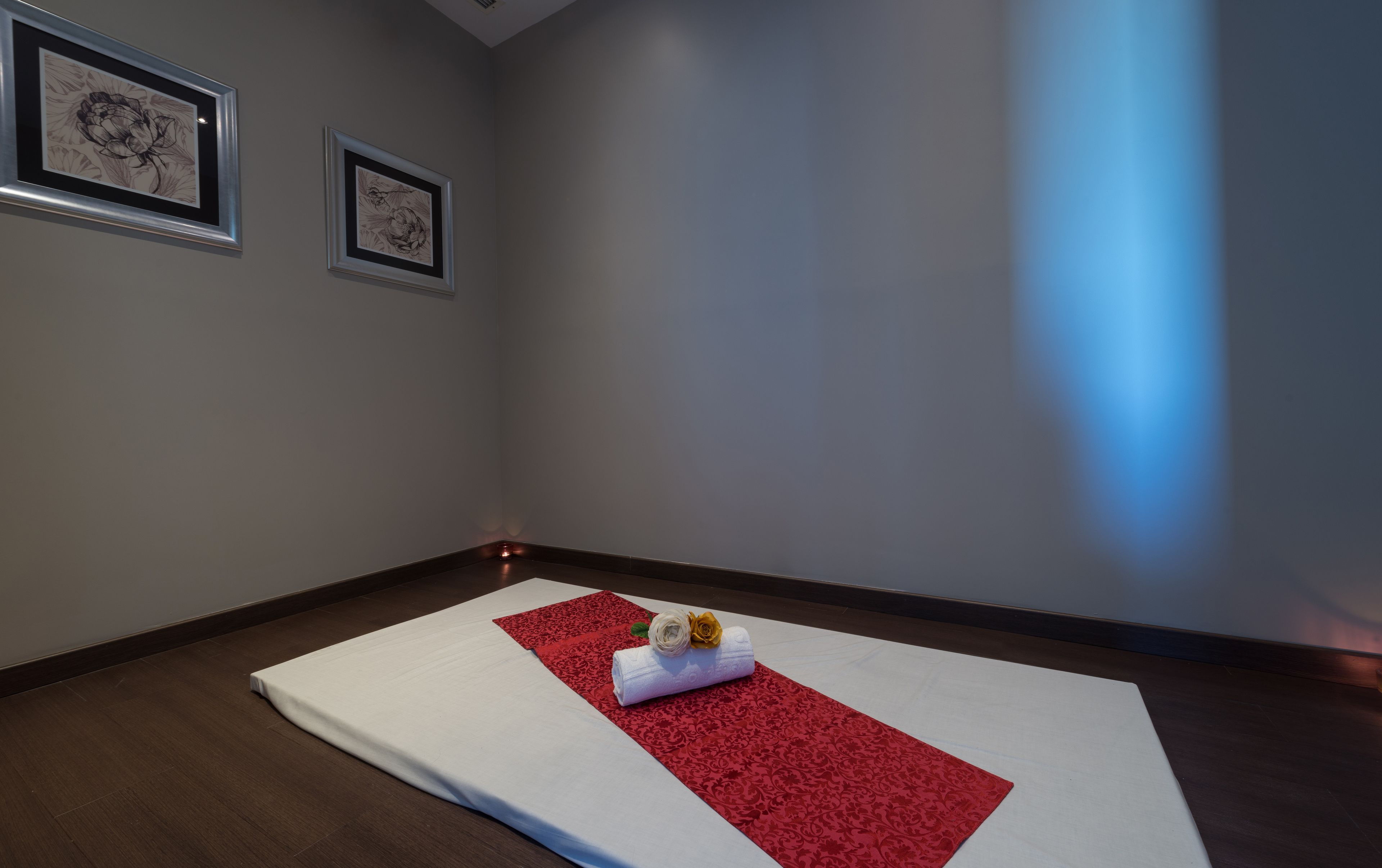 Ein Zimmer mit einem großen Bett, einem roten Zierläufer und zwei gerahmten Kunstwerken an der Wand.