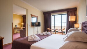 A hotel room with a large bed, a desk with a chair, a television, and a balcony with a view. -  Vila Gale Porto Centro Hotel (Porto)