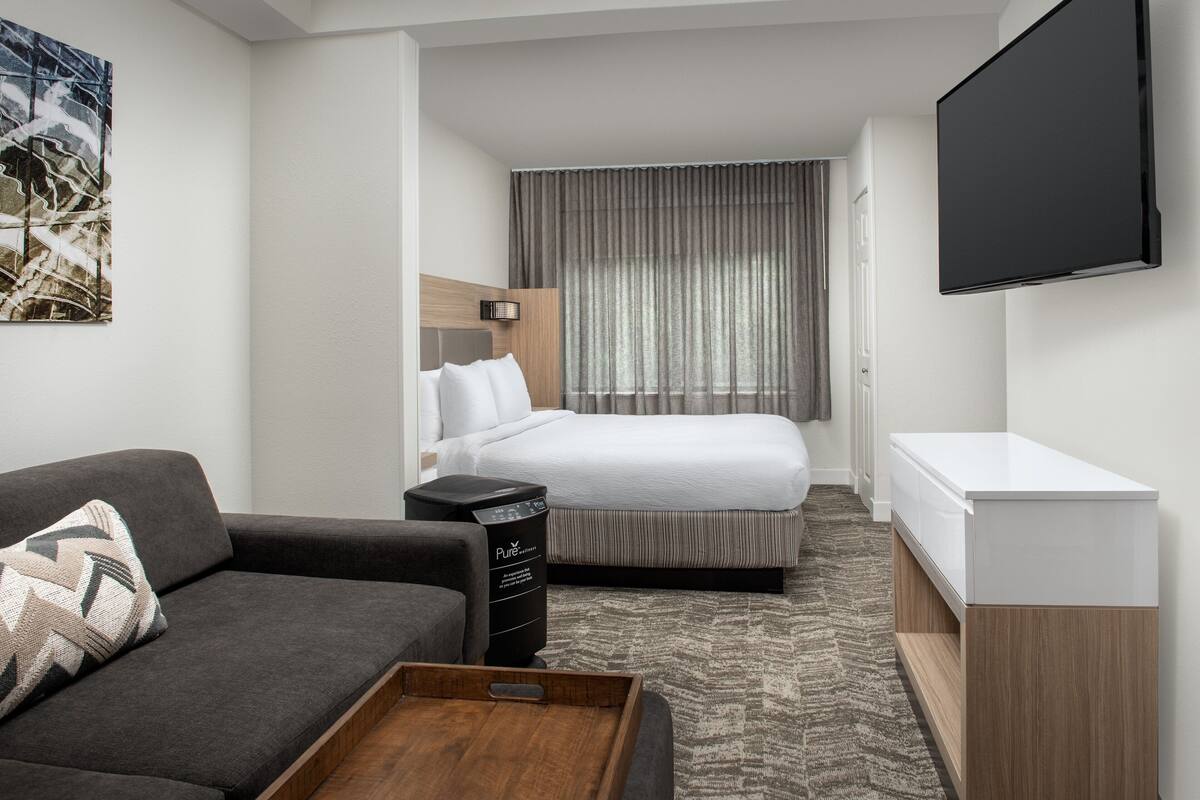A hotel room with a bed, a sofa, a TV, and a desk.