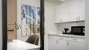 Una cocina moderna con gabinetes blancos, un microondas negro y una cafetera sobre la encimera.