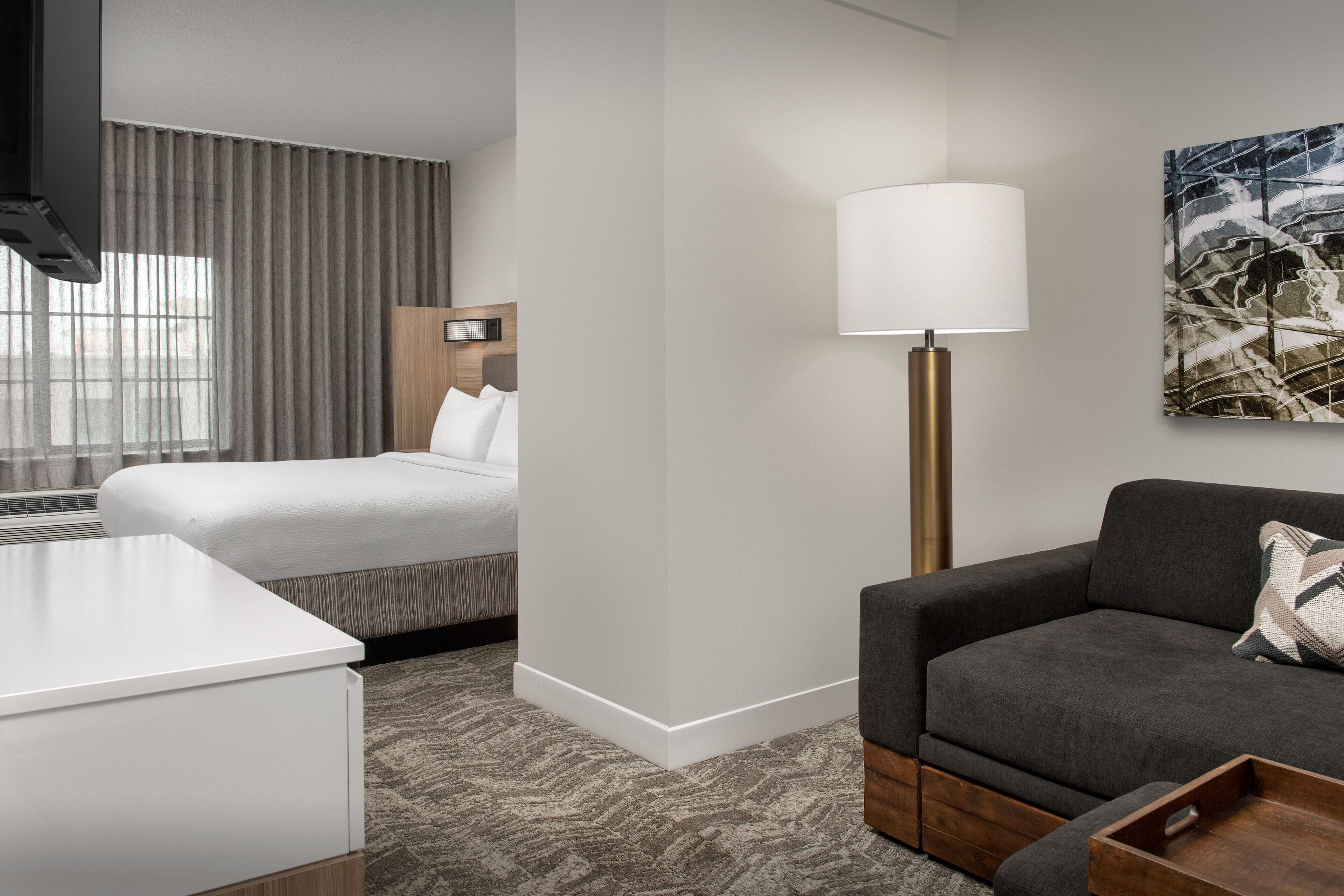 Une chambre d’hôtel avec un lit, un canapé, une lampe et un tableau au mur.