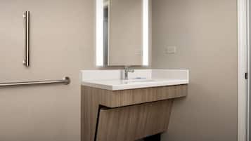 A modern bathroom with a wooden vanity, a white sink, and a mirror.