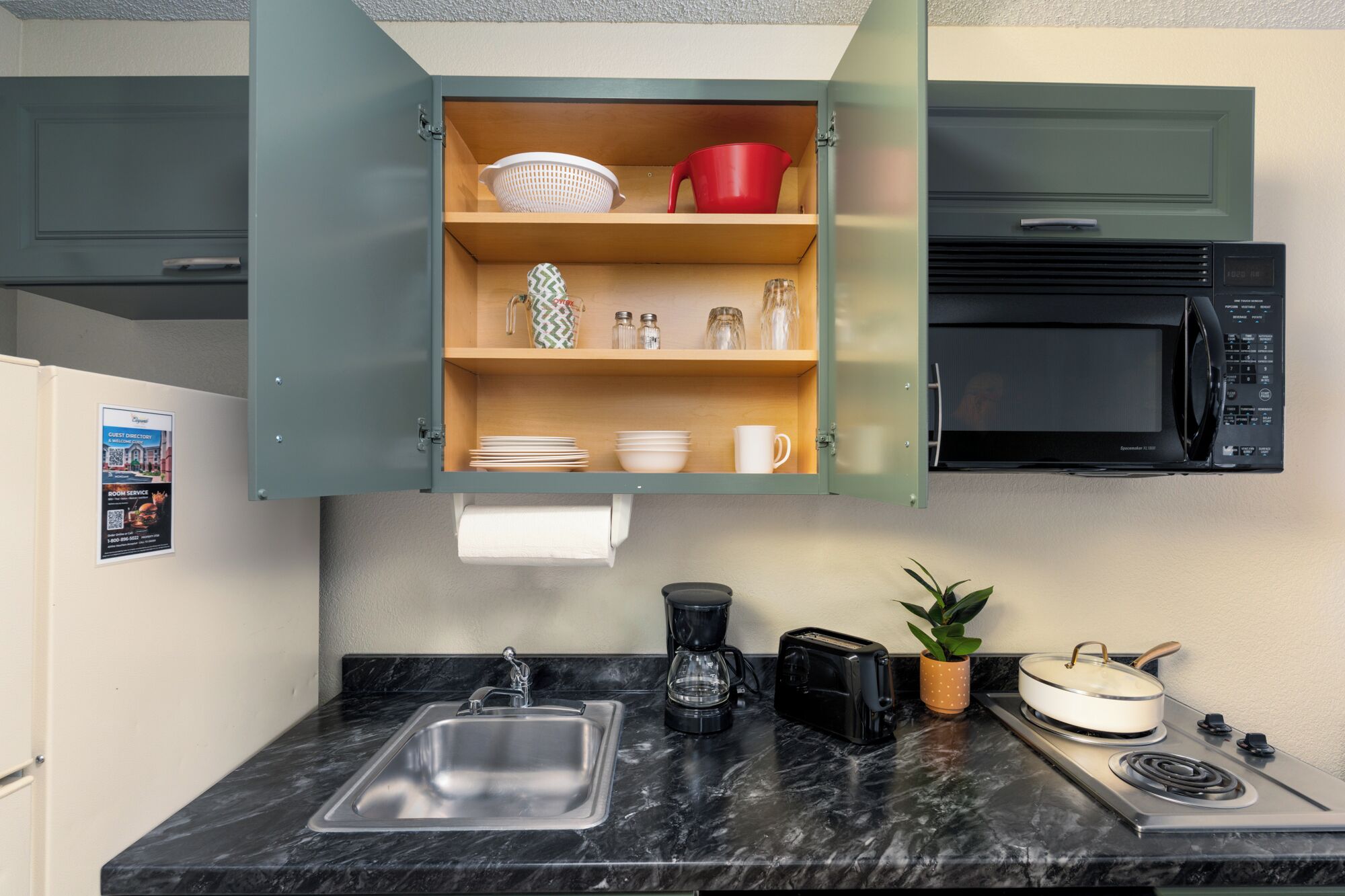 A kitchen with a built-in microwave, a coffee maker, a toaster, and a stove.