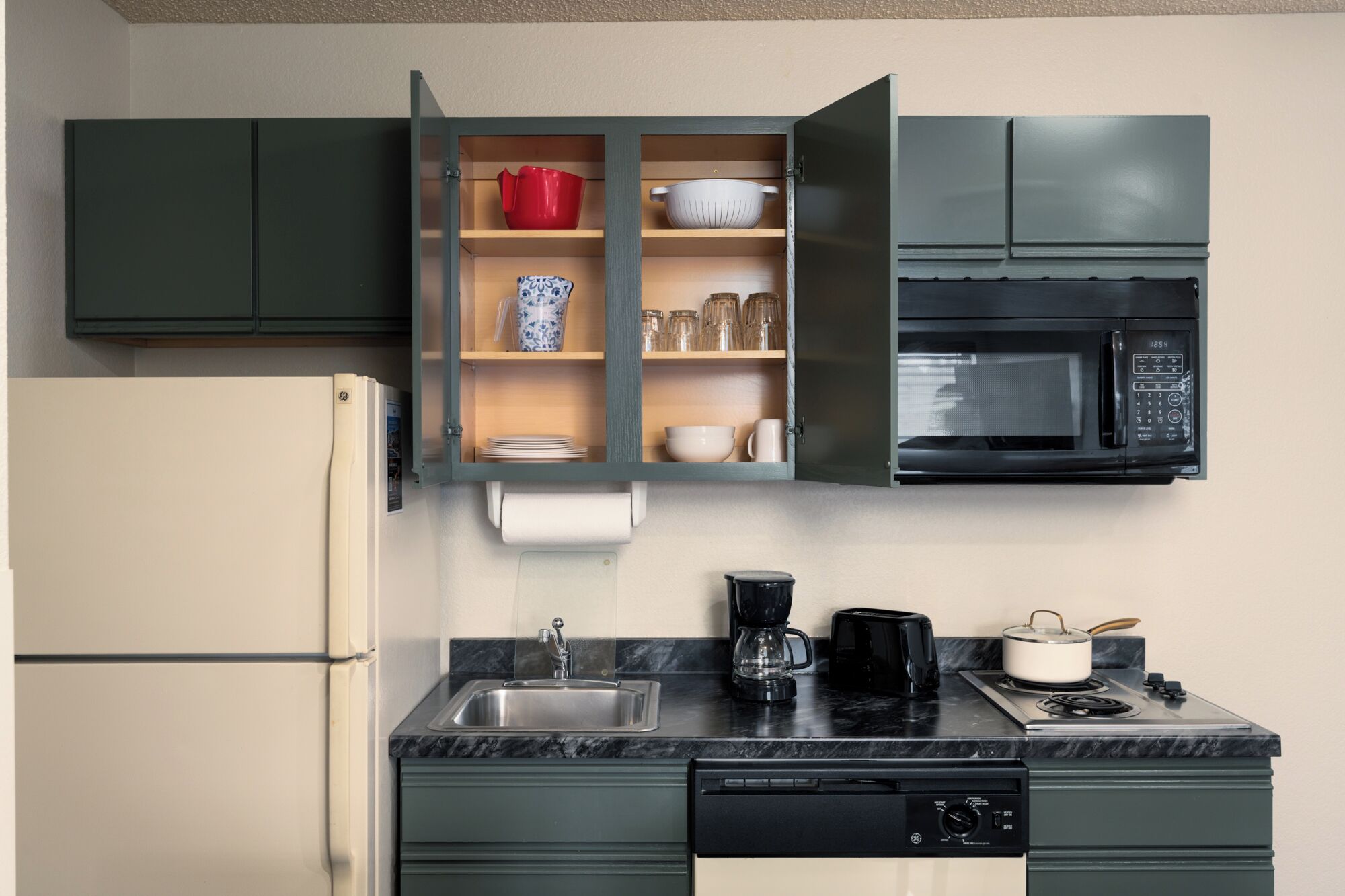 A compact kitchen with a built-in microwave, a coffee maker, and a dishwasher.