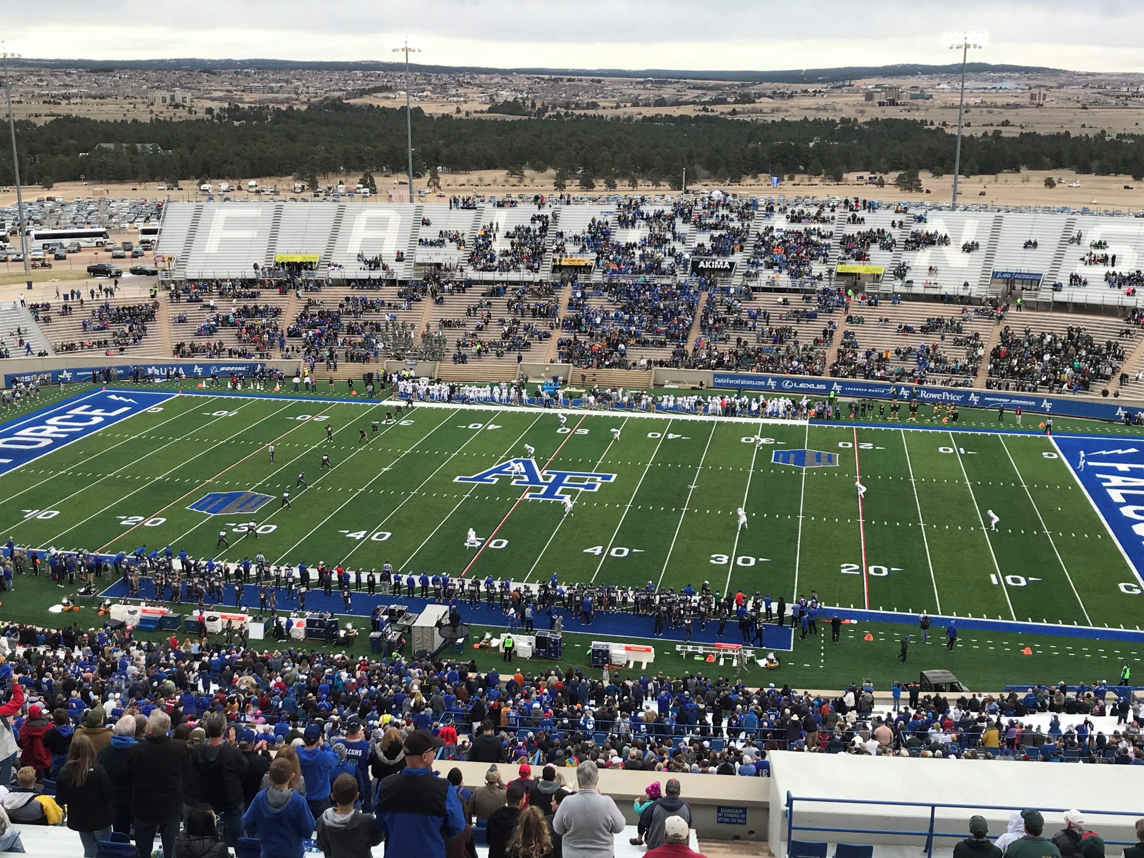 A stadium with a football field, bleachers, and a crowd of spectators.
