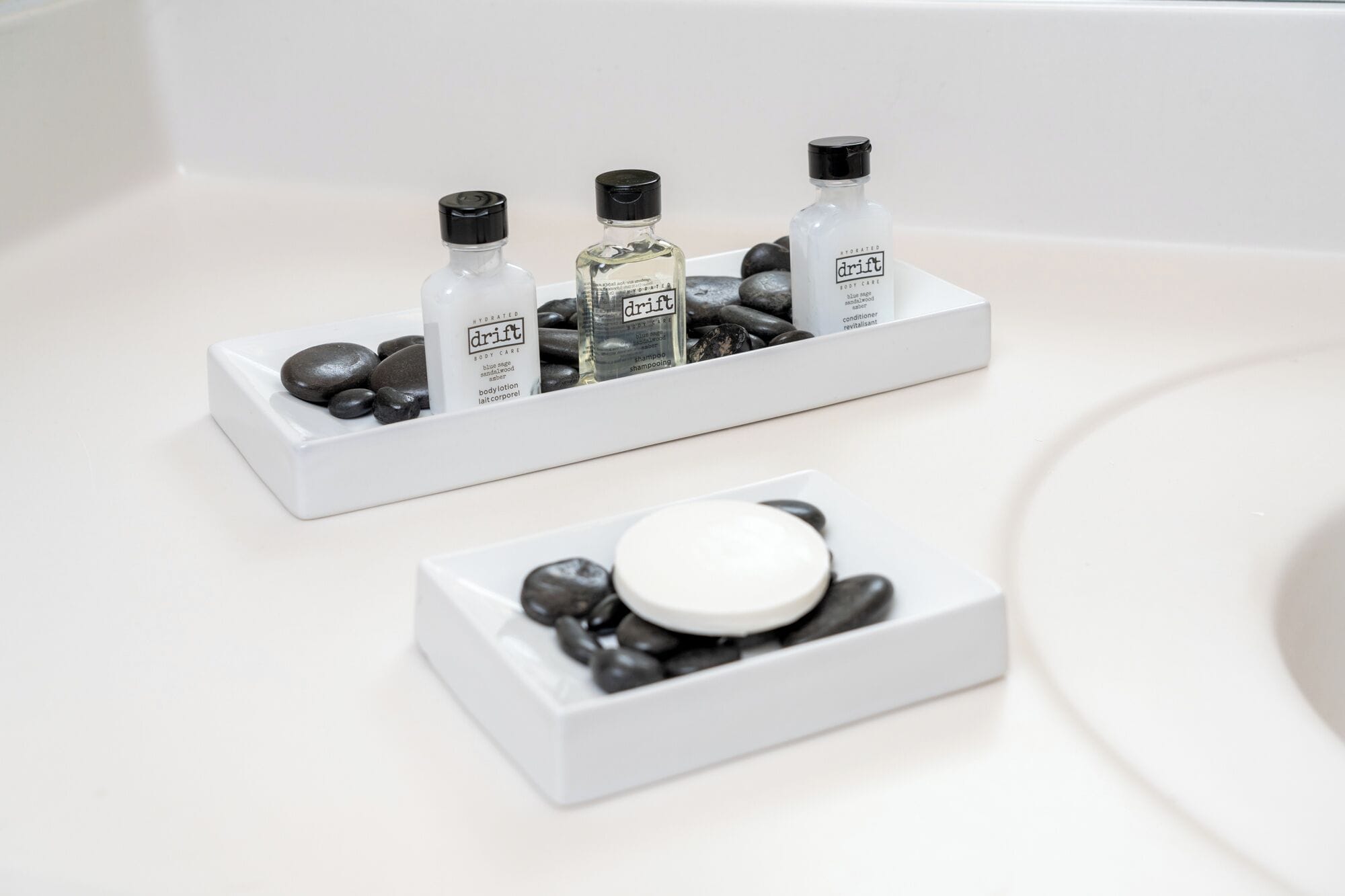 A bathroom with a white sink, two white rectangular containers holding toiletries, and a white soap dish.
