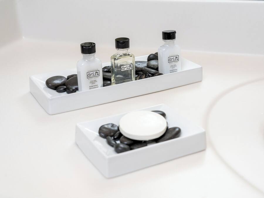 A bathroom with a white sink, two white rectangular containers holding toiletries, and a white soap dish.