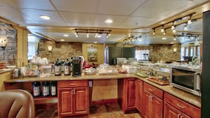 A spacious kitchen with granite countertops, wooden cabinets, and a stone accent wall. - MCM Elegante Suites (Colorado Springs)