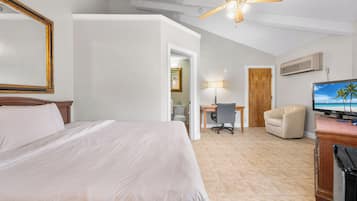 Ein Hotelzimmer mit Bett, Schreibtisch, Stuhl, Fernseher und Deckenventilator.