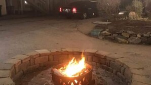 Ein Feuerkorb mit einem Backsteinring, umgeben von einer gepflasterten Fläche.