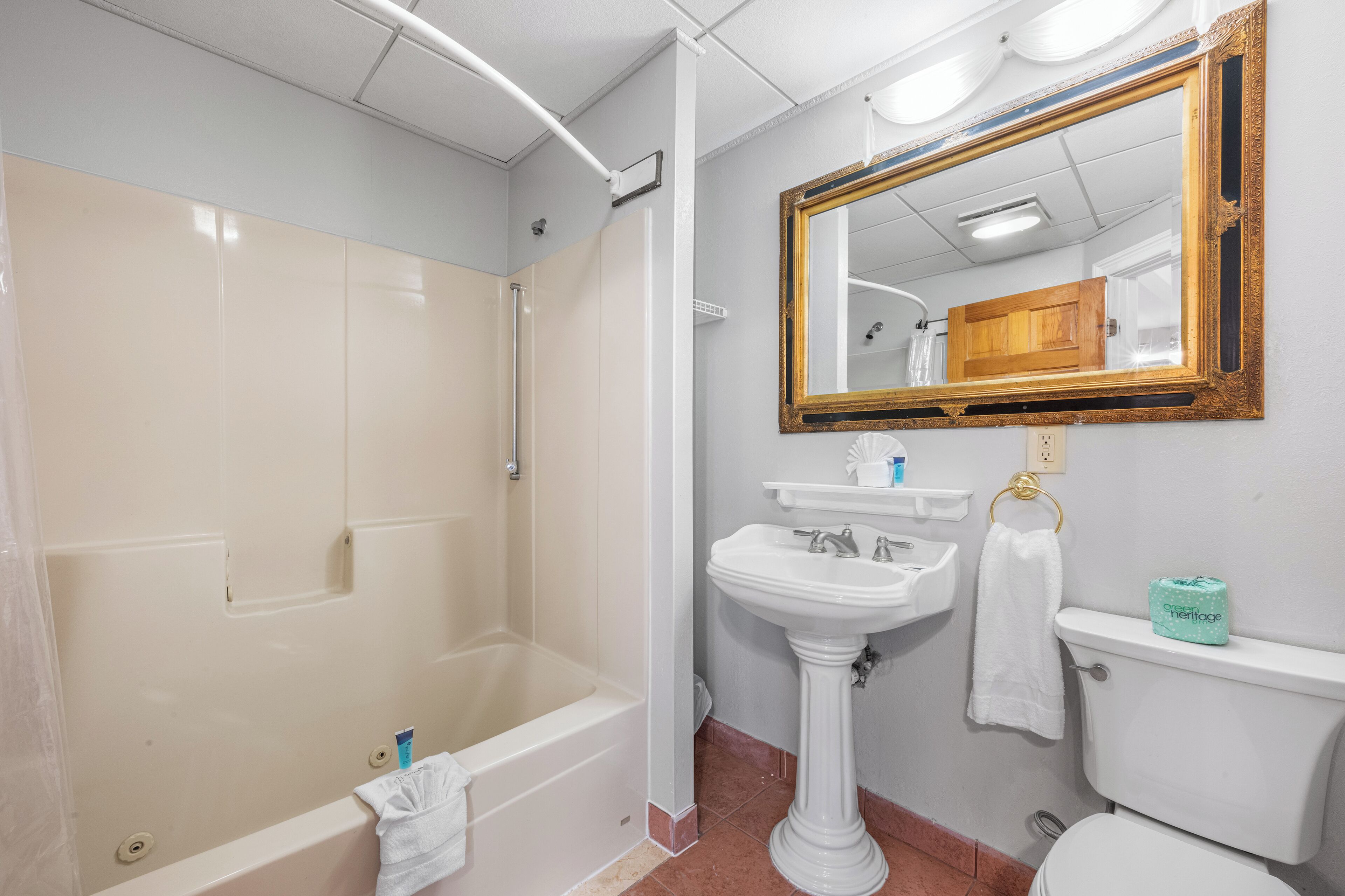Un baño con bañera, lavabo, inodoro y un espejo grande.