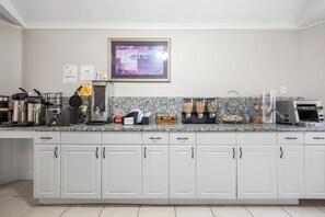 A kitchen with white cabinets, a granite countertop, a coffee maker, a waffle maker, and various food items. - Cedar Park Whirlpool Suites (North Stonington)