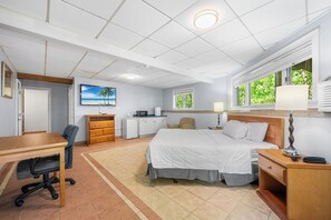 A hotel room with a bed, desk, chair, dresser, and a television on the wall. - Cedar Park Whirlpool Suites (North Stonington)