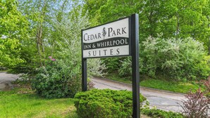 Schild des Cedar Park Inn & Whirlpool Suites, umgeben von üppiger Vegetation.