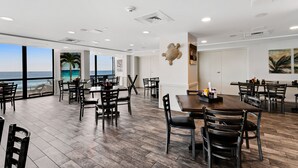 A spacious dining area with large windows overlooking the ocean, wooden flooring, and modern ceiling design. - Surfside Resort (Miramar Beach)