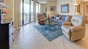 A spacious living room with a large window, a sofa, two armchairs, a coffee table, and a decorative vase. - Surfside Resort (Miramar Beach)