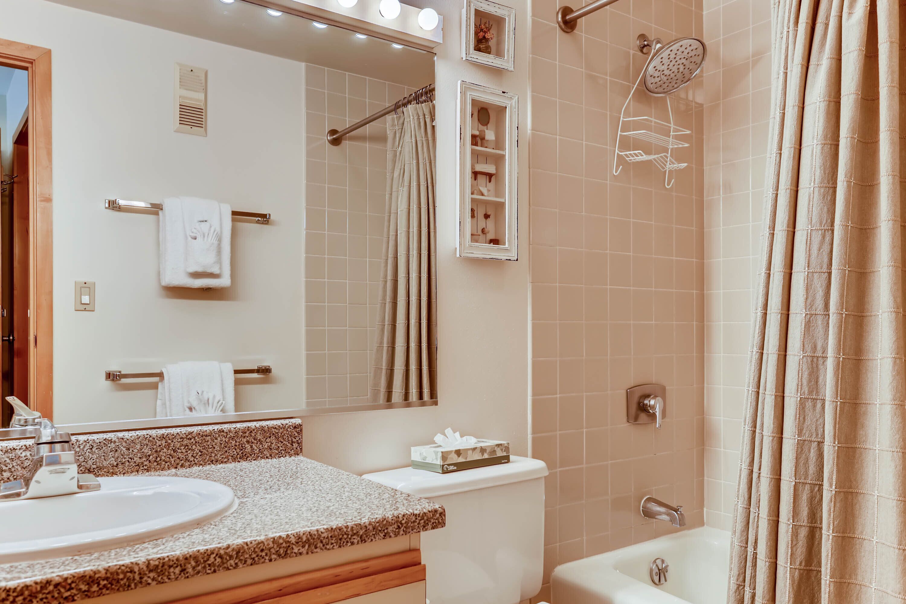 Une salle de bain équipée d’un lavabo, d’un miroir, d’un porte-serviettes, d’une douche et de toilettes.
