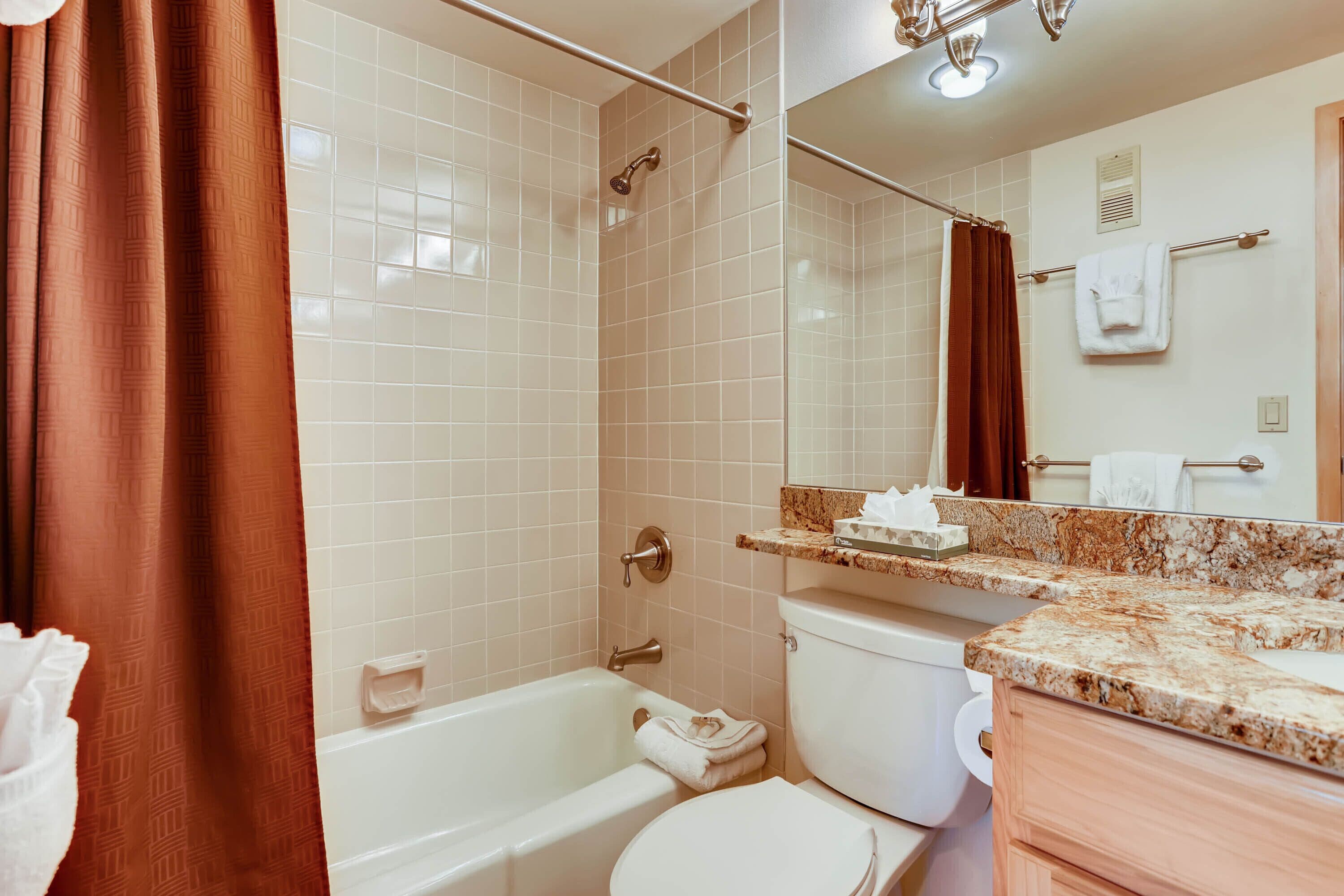 A bathroom with a bathtub, toilet, and a vanity with a mirror.