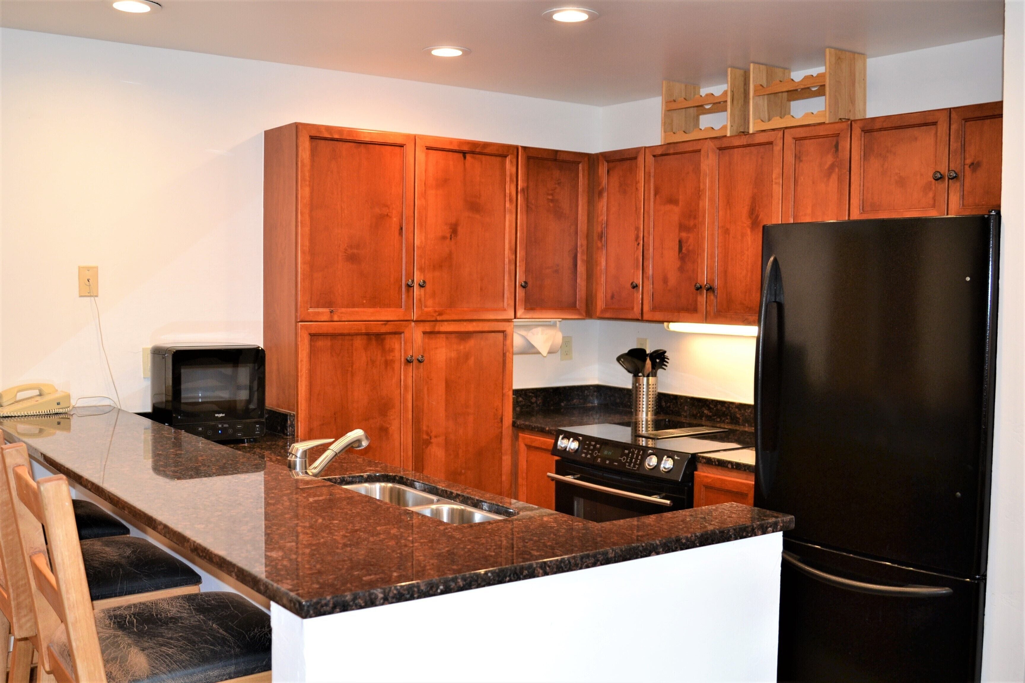 A kitchen with wooden cabinets, a black refrigerator, a stove, and a microwave.