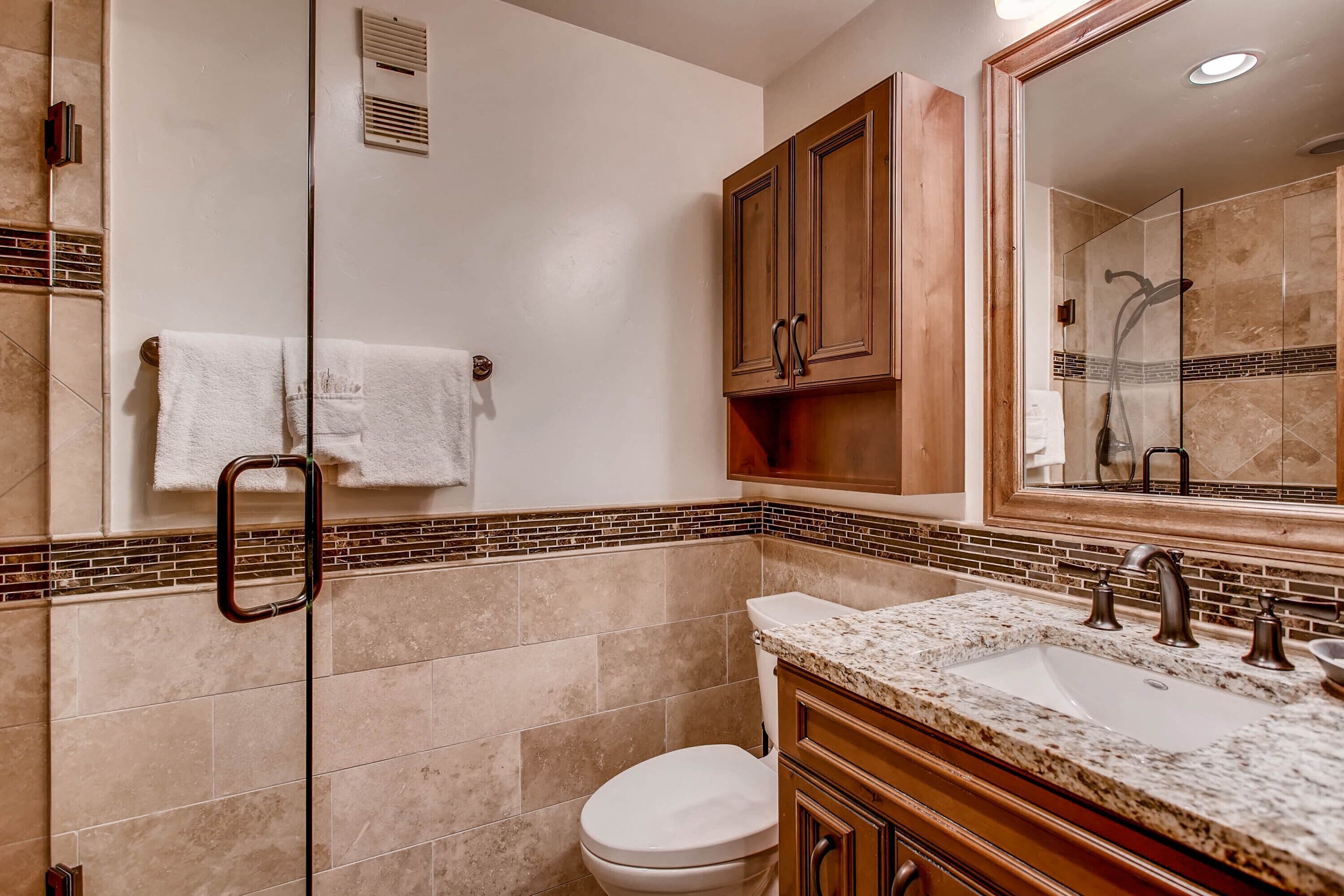 Une salle de bain avec un grand miroir, deux lavabos, des toilettes et une douche.